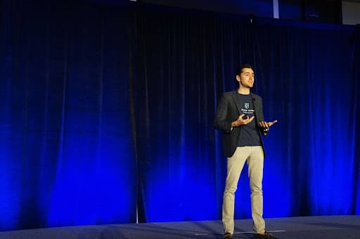 artist/speaker wearing black blazer talking on stage
