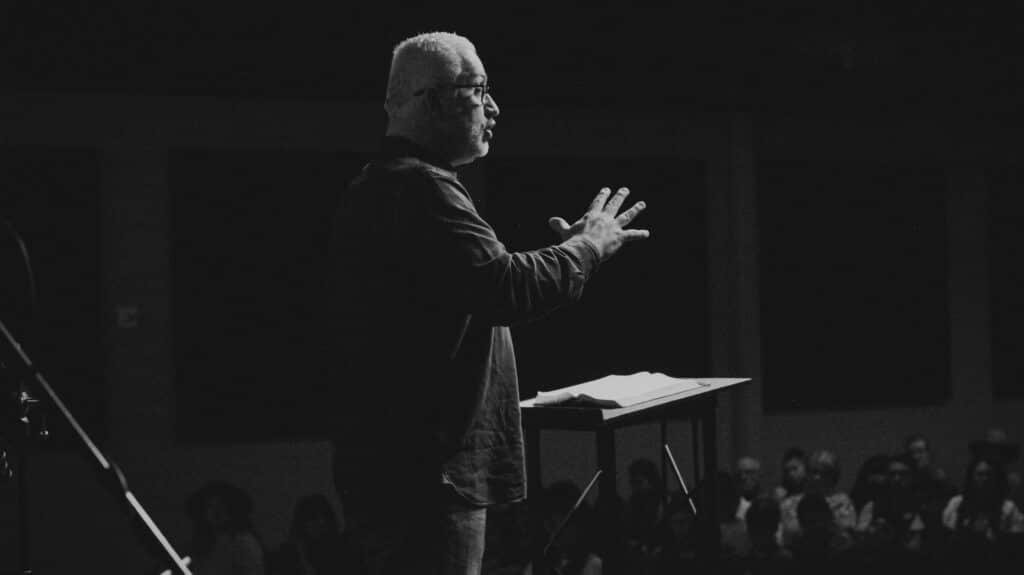a grayscale picture of a man professionally speaking towards the audience