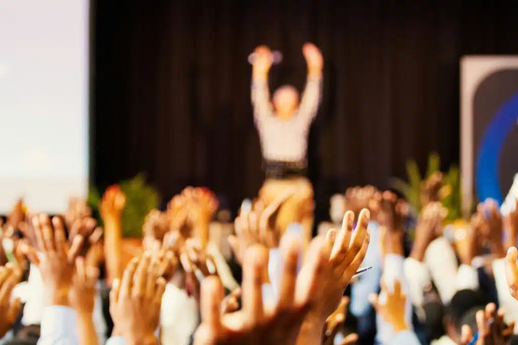 people raising hands with bokeh lights during an event | event planning tips
