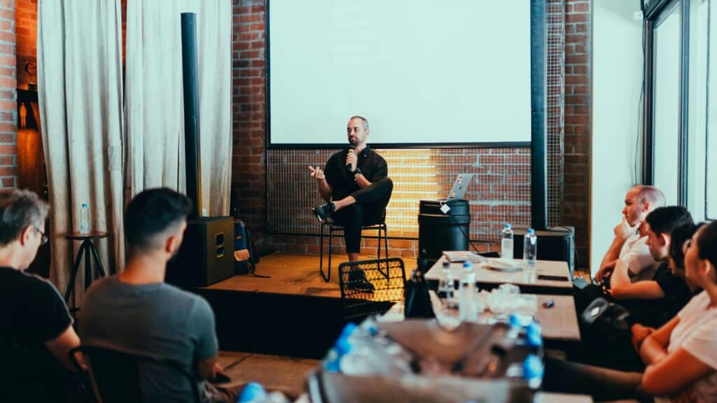 speaker talking to audience while seated | speaker branding