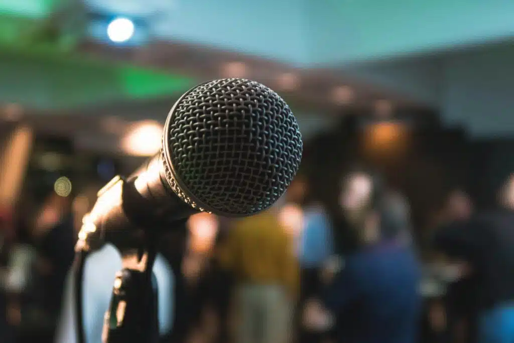 A bokeh of microphone with a crowd at the background | speaker proposal guide